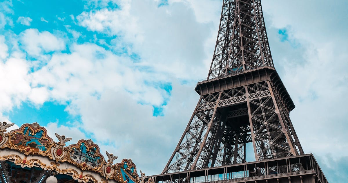 EU motorway tolls Eiffel Tower in Paris with vintage carousel in foreground under bright sky