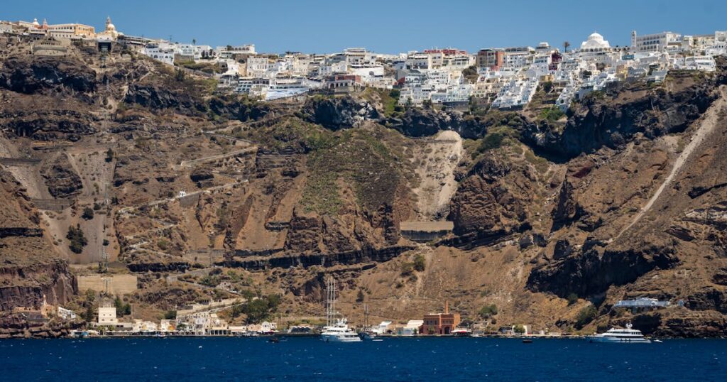 Vue imprenable sur l'architecture de la falaise de Santorin avec les bateaux dans le port en contrebas.