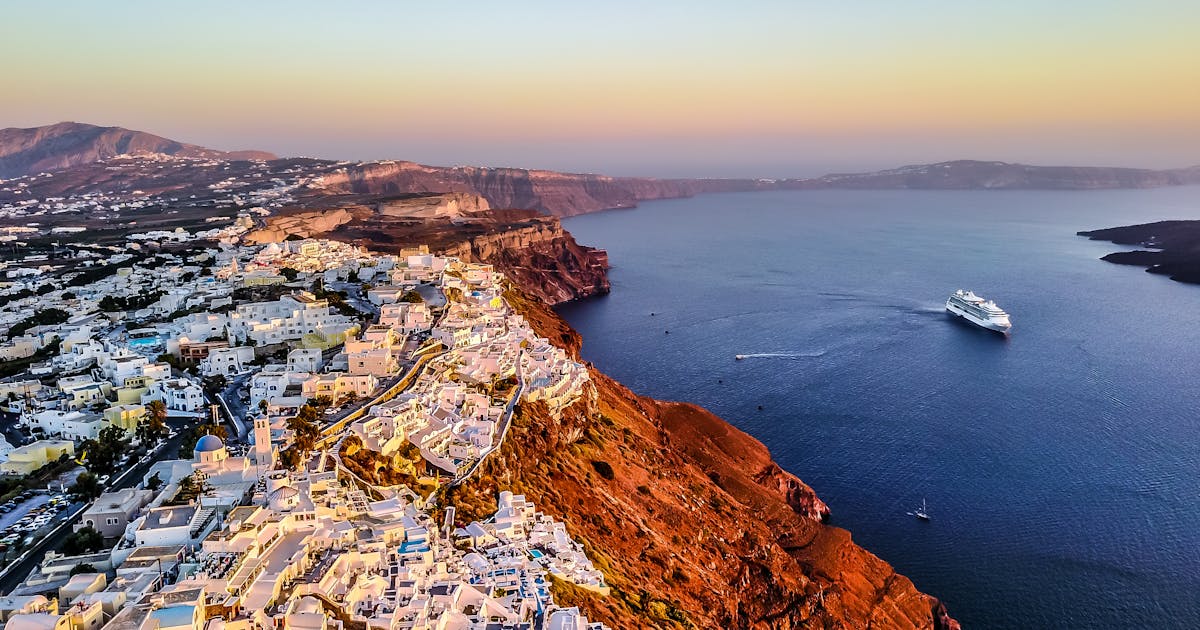 Pranvera e Lisbonës Pamje ajrore mahnitëse e bregdetit të Santorini në perëndim të diellit me anijen e kryqezimit