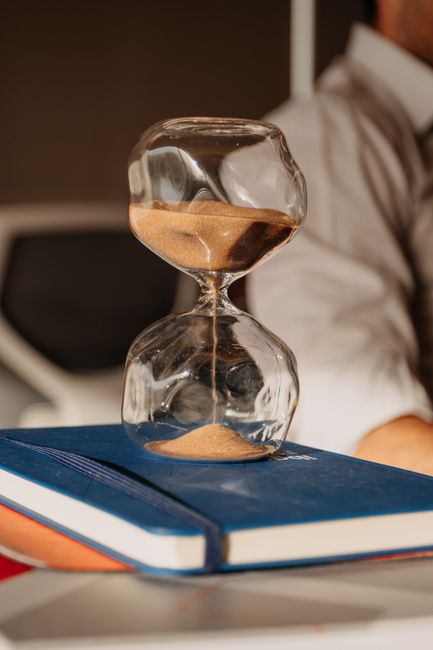 Hourglass on a desk beside a laptop