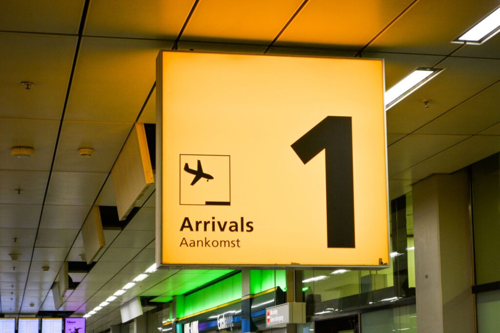 Wide view of a modern European airport arrivals hall with signage and travellers