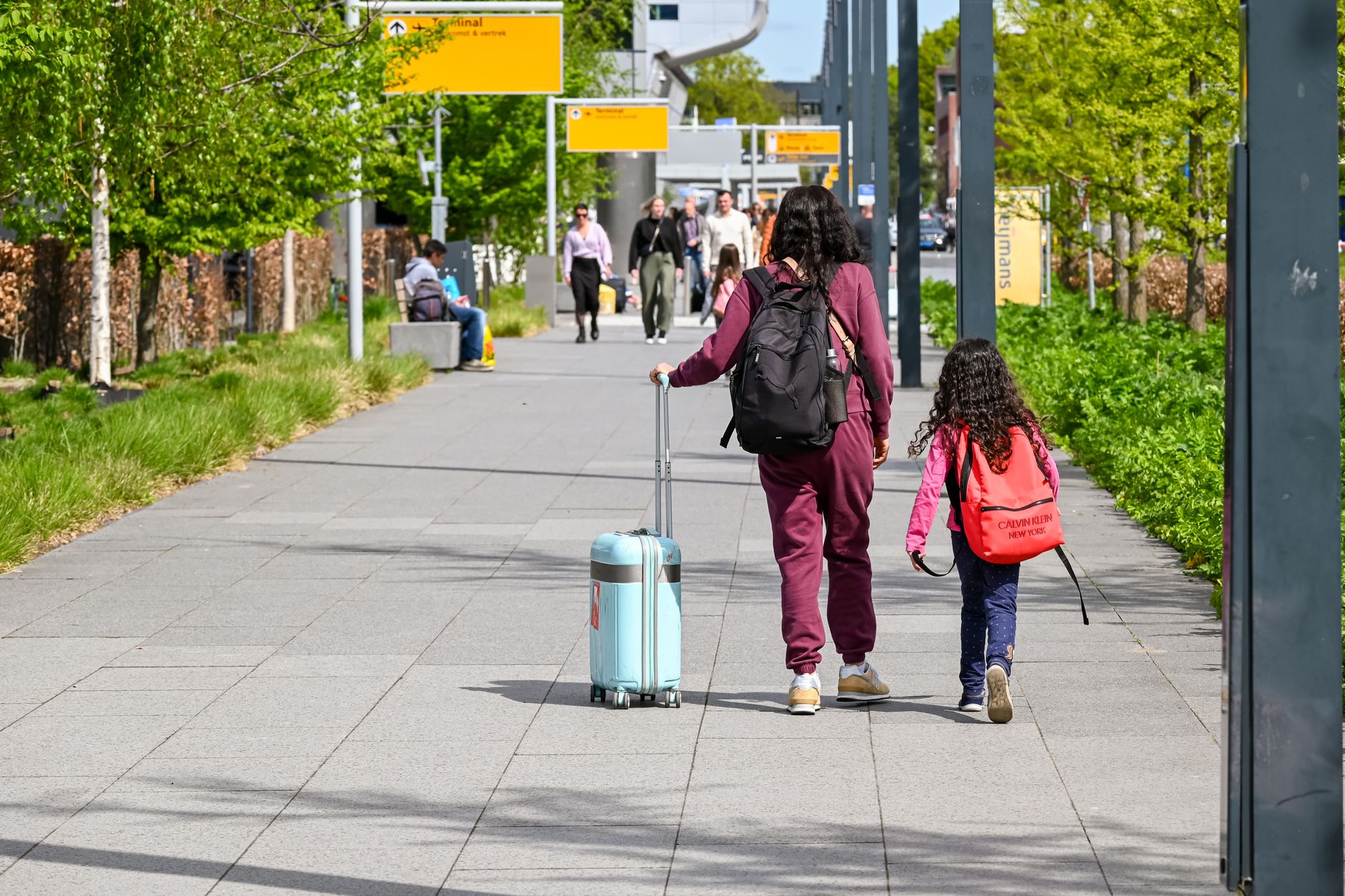 Family with suitcases and children waiting together in a summer airport queue